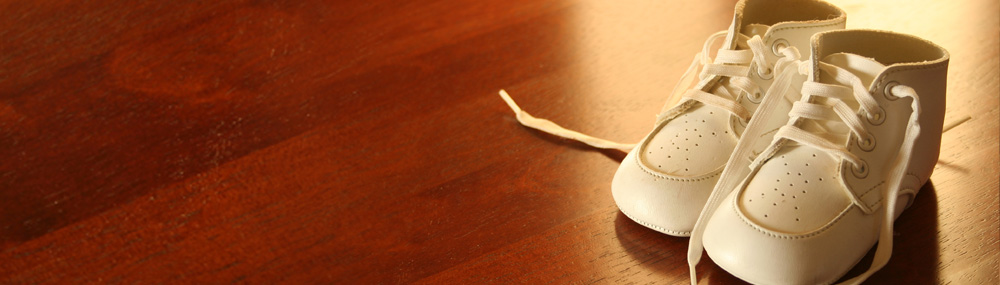 Un par de zapatos de bebé blancos sobre un piso de madera.